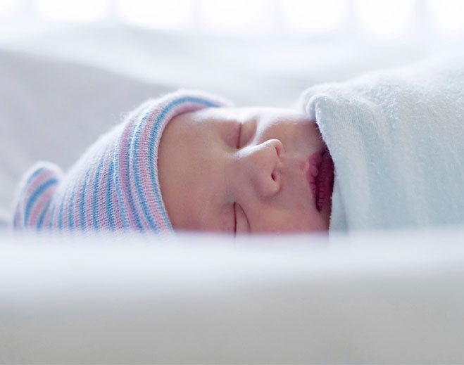 Newborn sleeping swaddled in hospital blanket