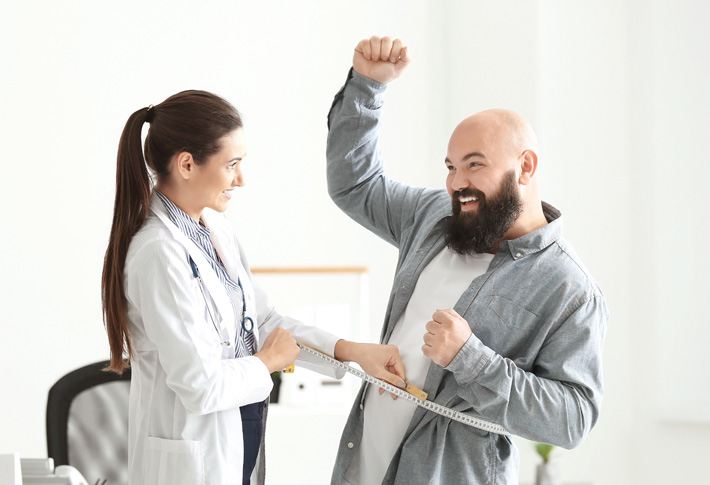 Doctor measuring patient’s waist with tape